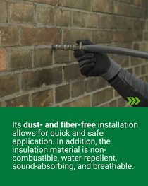 Gloved hand inserting a hose into a drilled opening in a brick wall for the application of insulation material.