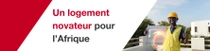 Un homme portant un gilet de sécurité jaune et un casque de sécurité se tient devant un bâtiment, tenant un carreau de construction. Des tourbillons lumineux apparaissent près de la main de la personne. Le texte indique : « Des logements innovants pour l’Afrique. »