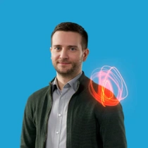 Ein männlicher BASF-Mitarbeiter steht in einer dunkelgrünen Jacke und hellgrauem Hemd vor einem blauen Hintergrund. Ein rot-orangefarbener Lichtwirbel schwebt über seiner Schulter. Ein männlicher BASF-Mitarbeiter steht in einer dunkelgrünen Jacke und hellgrauem Hemd vor einem blauen Hintergrund. Ein rot-orangefarbener Lichtwirbel schwebt über seiner Schulter.