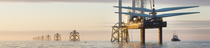 Une éolienne en cours de construction depuis une plate-forme dans une mer calme au coucher du soleil. Une éolienne en cours de construction depuis une plate-forme dans une mer calme au coucher du soleil.