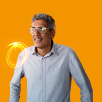 A male BASF employee in a grey shirt standing against a orange background, a light swirl hovers around his shoulder.  