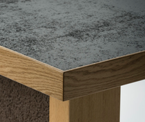 Eine Tischecke mit einem hellen Furnier an der Seite und einer dunklen Oberfläche  