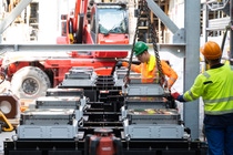 Am Haken: Der letzte Transformator wird per Kran in die Demonstrationsanlage gehoben und in Millimeterarbeit platziert und ausgerichtet. Am Haken: Der letzte Transformator wird per Kran in die Demonstrationsanlage gehoben und in Millimeterarbeit platziert und ausgerichtet.