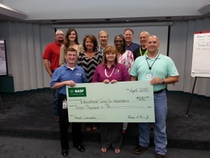 BASF makes annual contribution to the Educational Center for Independence and presents hundreds of newspapers to the organization. First row from left to right: George Vann, Vice President of BASF McIntosh, Denise Taylor, ECI Executive Director and John Weaver, Quality and Logistics Manager. Second row left to right:  Roger Hadley, Plant Safety Coordinator, Chrissie James, Maintenance Systems Specialist, Rena Whigham, Site Controller, Bill Napper, Group Leader – Analyzer and Intermediate Testing, Gail Boykin, Human Resources Generalist, Bill Cox, Reliability Engineer and John Zimmerman, Maintenance Manager.